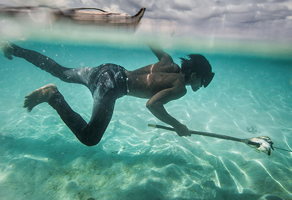 A young Bajau man named Dido fishes for coral fish and shells off Mantabuan Island.