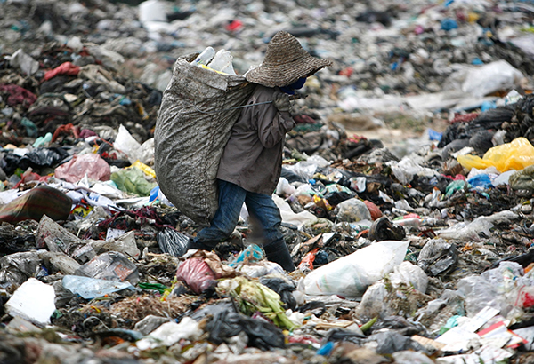 A man looks for plastic to recycle at a garbage site in Malaysia.