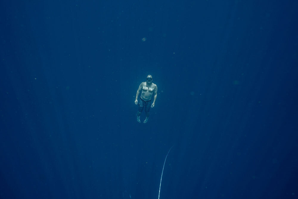 A man floats, suspended in the blue ocean