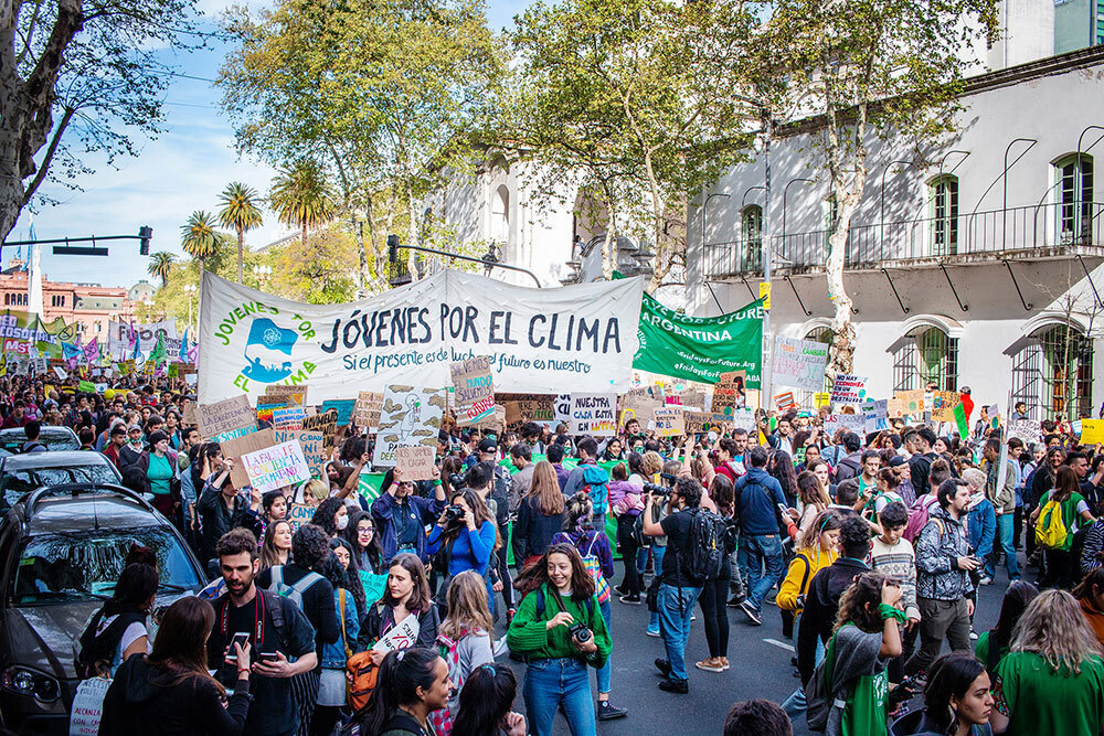 A crowd marches down a street holding signs