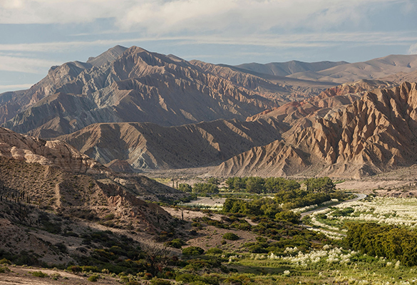 Shadows fall from mountain ridges to a green valley in Salta, Argentina.