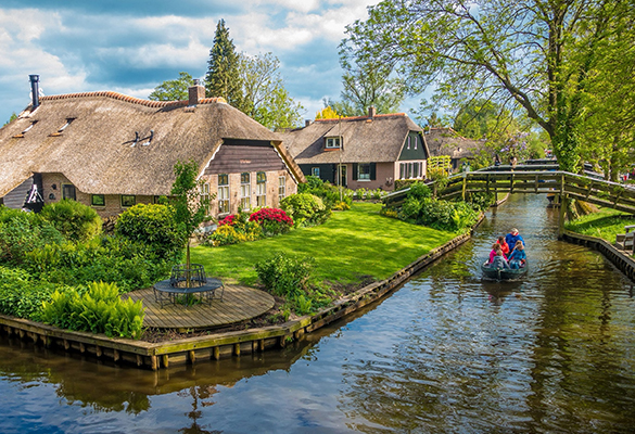 A boat plies a canal in Giethoorn, a Dutch village built on small peat islands without roads or cars.