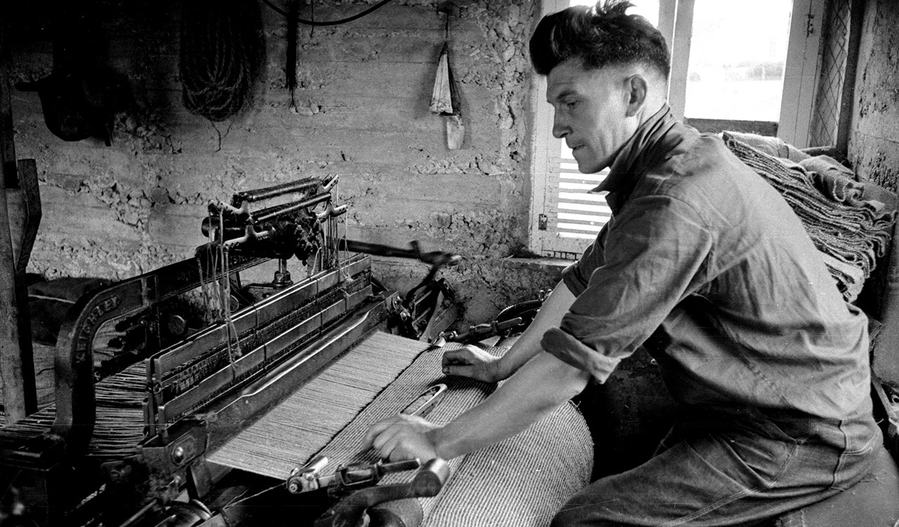 In this 1955 photo, a weaver in the Outer Hebrides is shown producing Harris Tweed on a foot-pedal loom. The centuries-old textile tradition carries on in these remote islands off the west coast of Scotland.