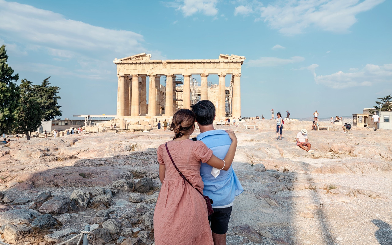 A couple visits the Acropolis in Athens, Greece. The columned Parthenon is usually surrounded by tourist crowds, but this year, due to the novel coronavirus, tourism to the country has dropped precipitously since March 2020.