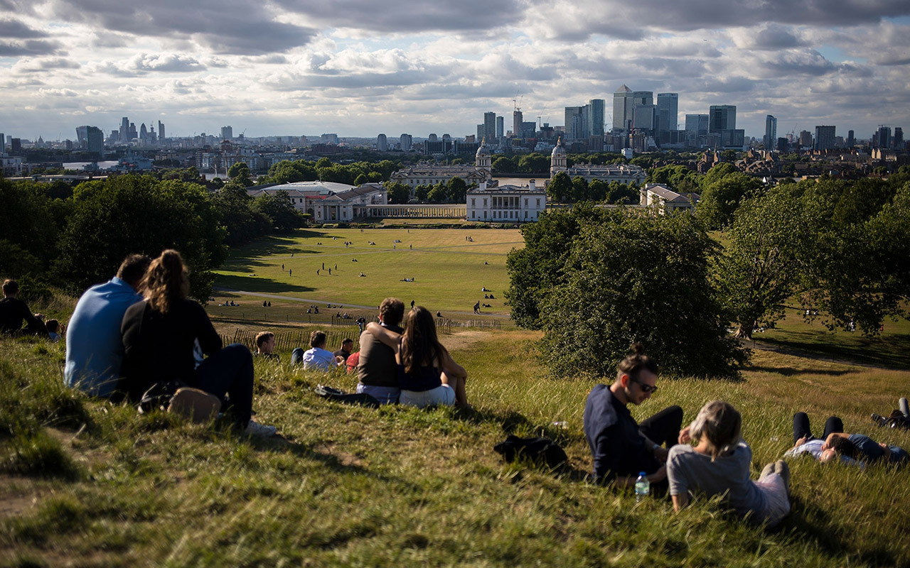 People spend the afternoon at Greenwich Park and enjoy the London skyline. London is set to become the first National Park City. The idea is that citizens will make cities greener, healthier, and wilder to get more people to spend more time outside.