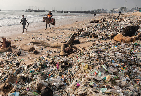 Tourists ride a horse on Kedonganan Beach, Bali, January 27, 2019. Every year during the wet season, from November to March, trash by the ton washes ashore, earning it the nickname garbage season.