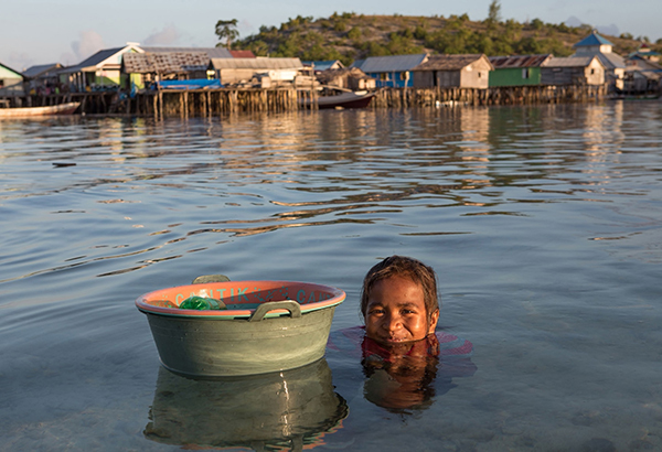 A young girl on Indonesia's Toropot Island collects sea urchins in the shallow water near her home.