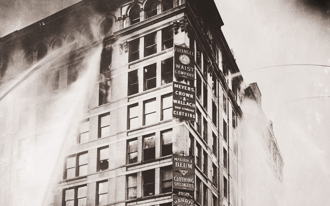 Fire hoses spray the upper floors of the Asch Building—headquarters to the Triangle Shirtwaist Company—during the 1911 fire in New York City that shocked the U.S. into developing new worker safety standards.