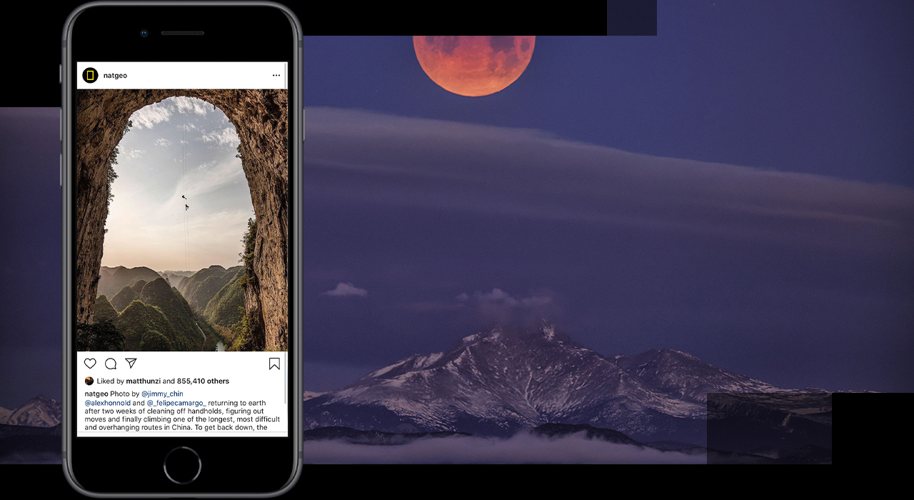 A mobile device showcases a photo @natgeo on Instagram. The lunar eclipse of a super blue blood moon is shown over Colorado’s Mount Meeker and Long’s Peak.