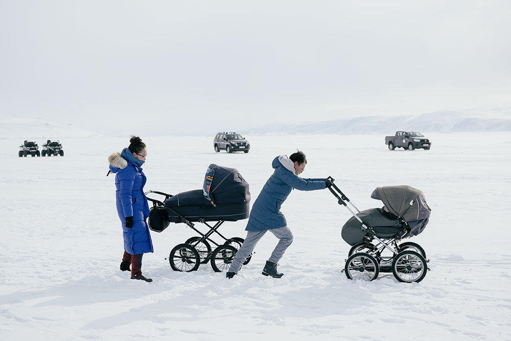 Two women push strollers across sea ice