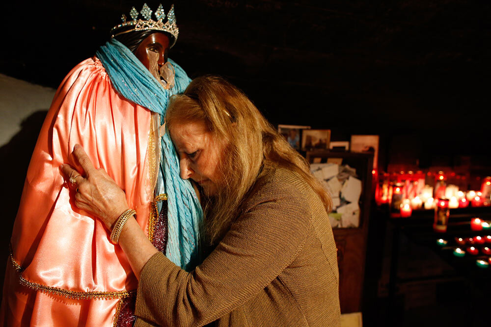 a Roma pilgrim embraces a statue of Santa Sara