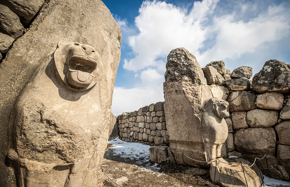 Carved stone lions flank a gate made of large stones