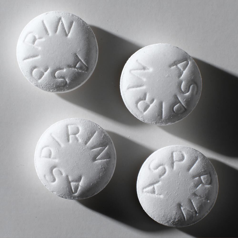 Four white aspirin tablets on a white background.