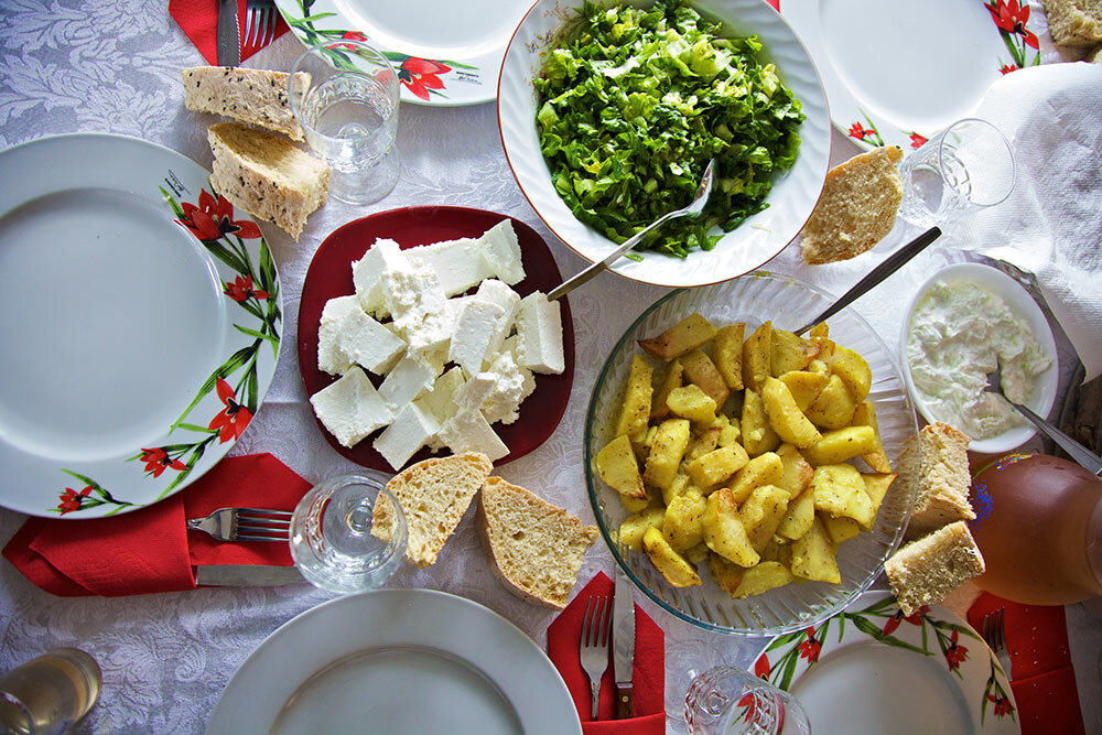 a dinner spread including feta cheese, bread, and vegetables