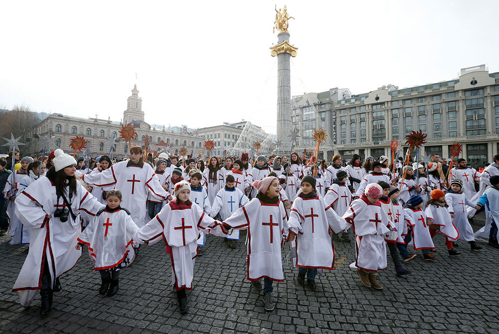 A picture of kids wearing white outfits holding hands in a square