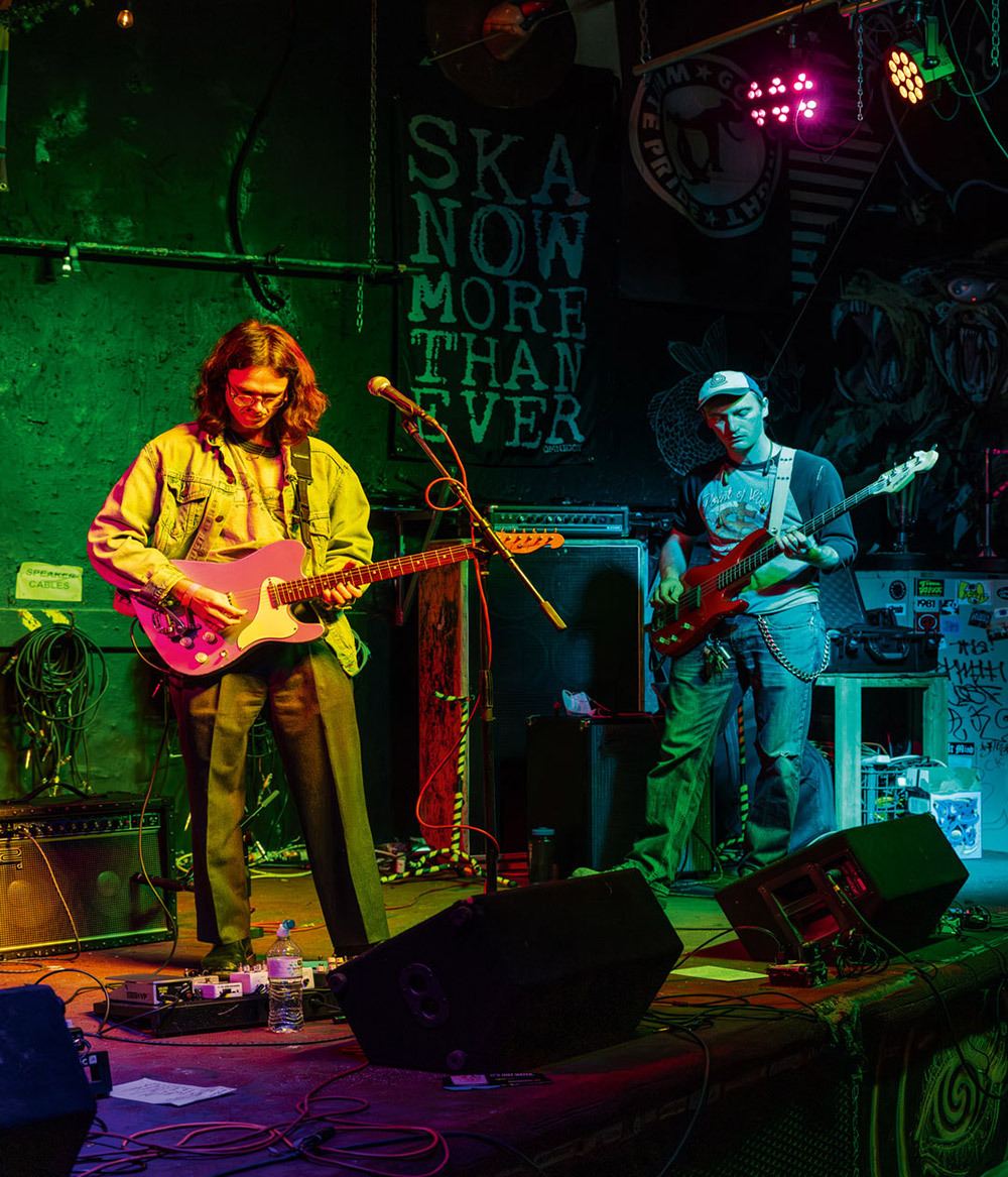 Two men stand on stage playing guitars