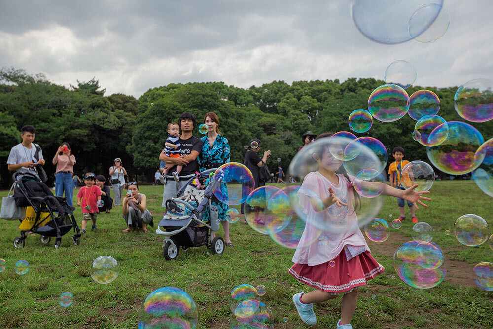 A girl runs through bubbles in a park