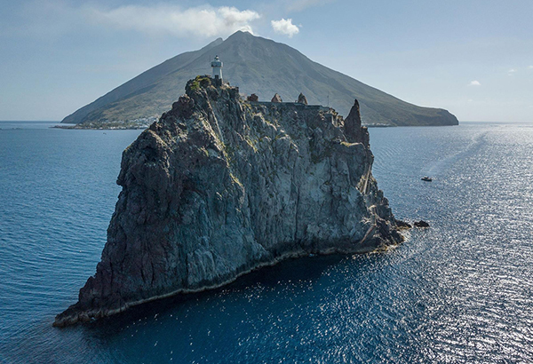 Italy’s volcanic Stromboli island looms behind its uninhabited sister island Strombolicchio in the Tyrrhenian Sea.