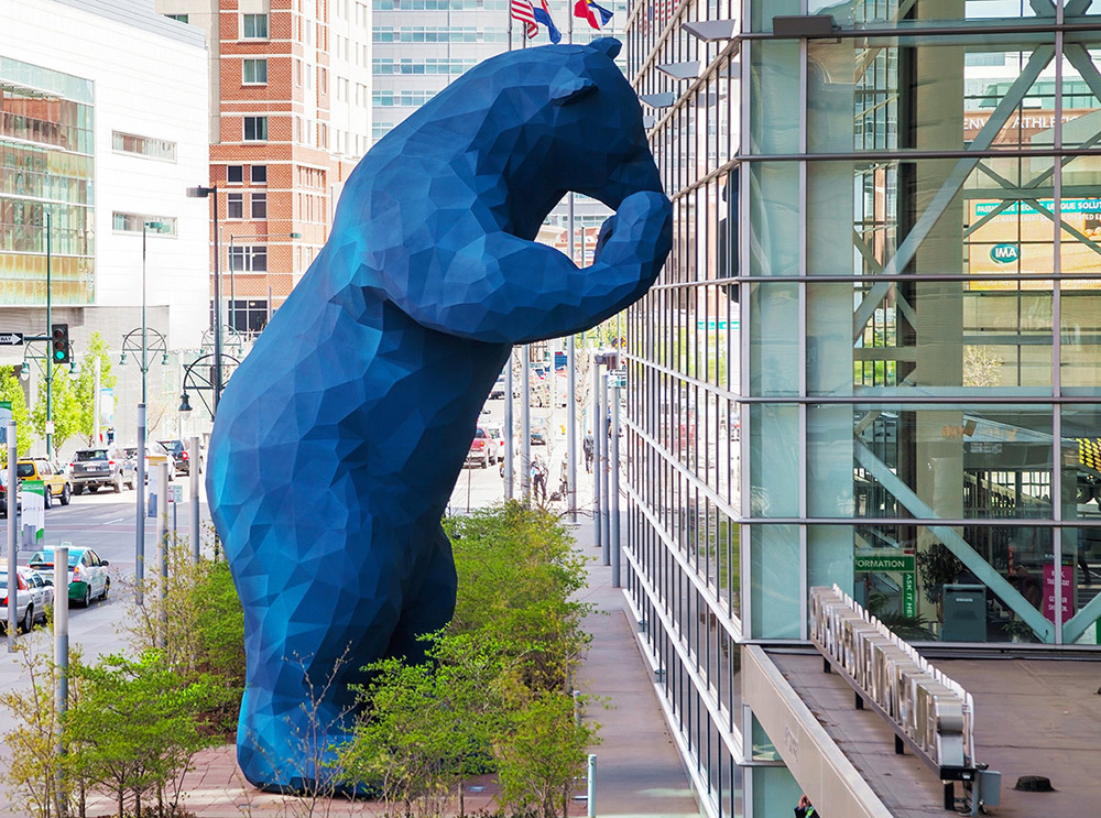 A giant bear sculpture facing an building window.