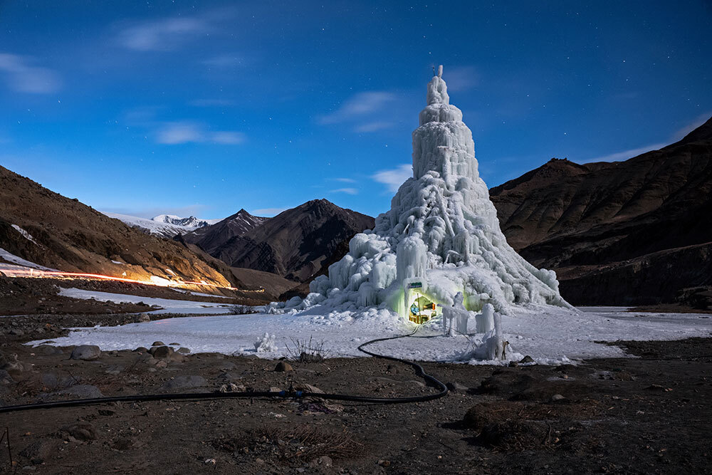 An ice stupa, or artificial ice tower, with a cafe built into its base