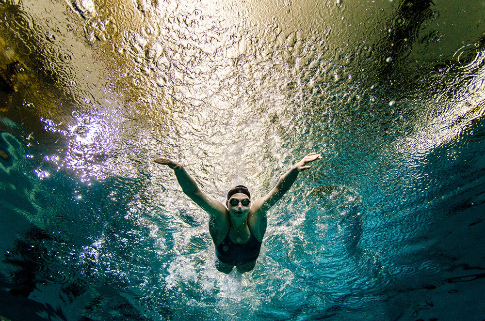 A woman swimming the butterfly stroke, seen from below with light rippling