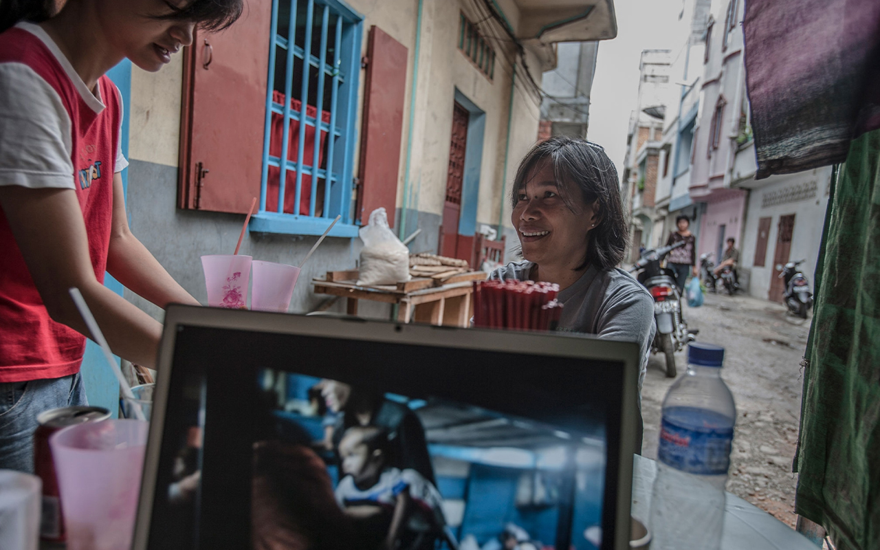 Zamira Loebis (also known as Tatap, or Tap) sits across from photographer John Stanmeyer in Selat Panjang, Indonesia, as he edits photographs from previous days on his laptop.