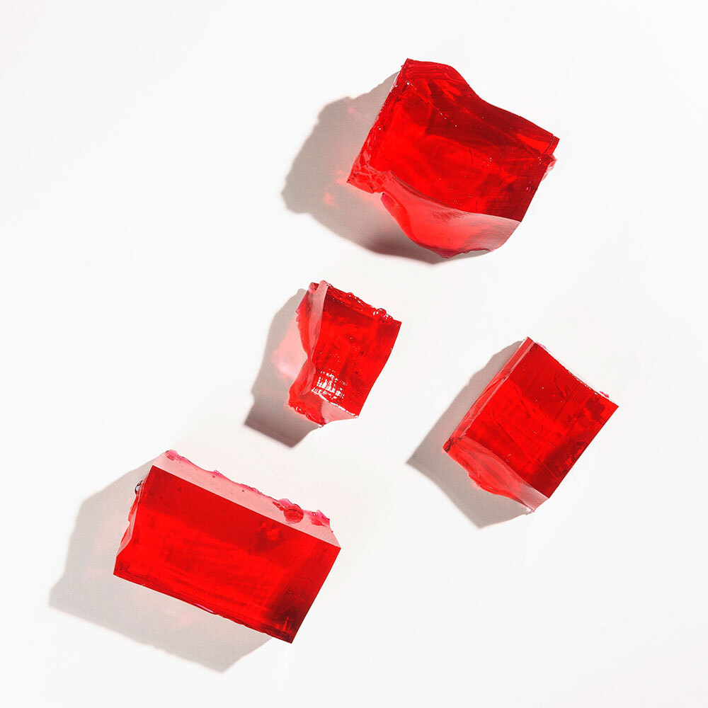 Chunks of red gelatin sit isolated on a white background.