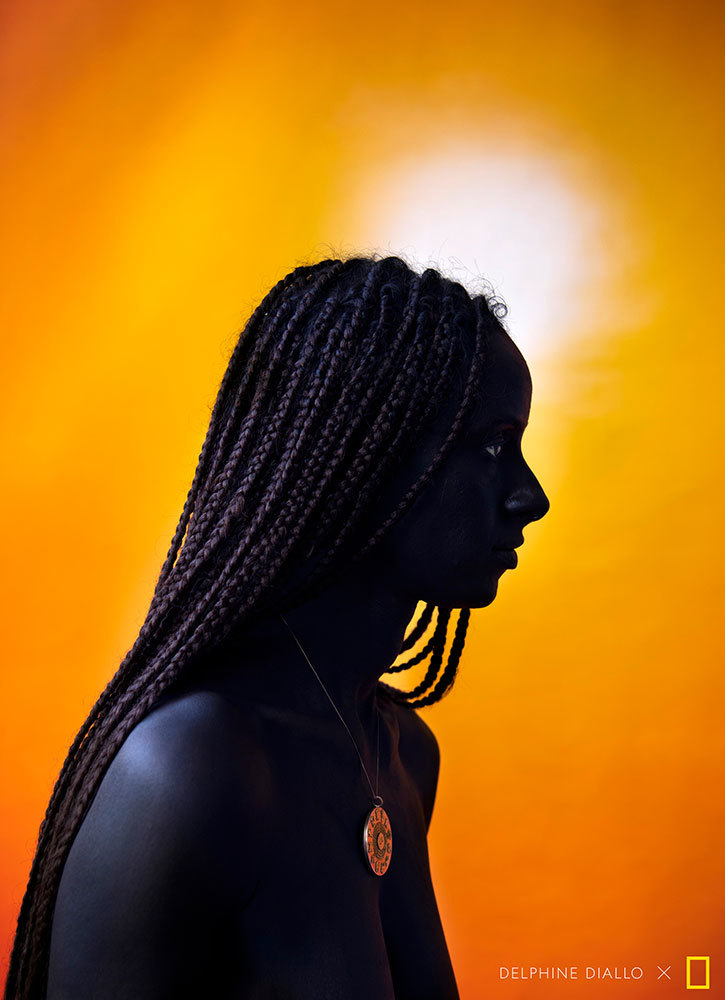 A picture of the side profile of a woman with braided hair and a large pendant necklace