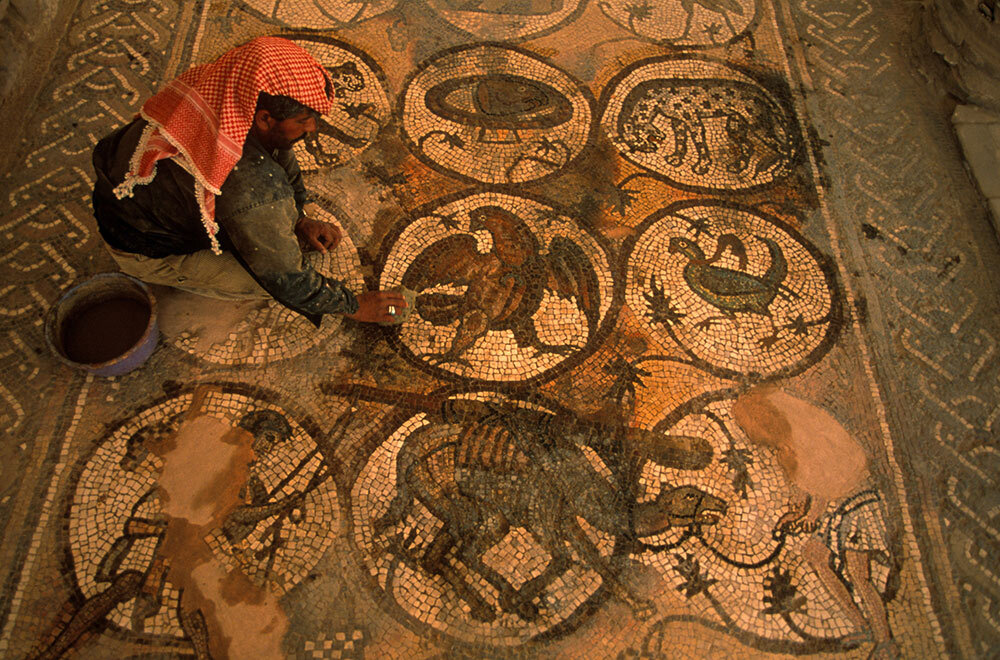 In Petra, Jordan, a Bedouin examines a Roman mosaic found in the floor of a fifth-century Byzantine church. The ancient city is Jordan's most-visited tourist attraction.