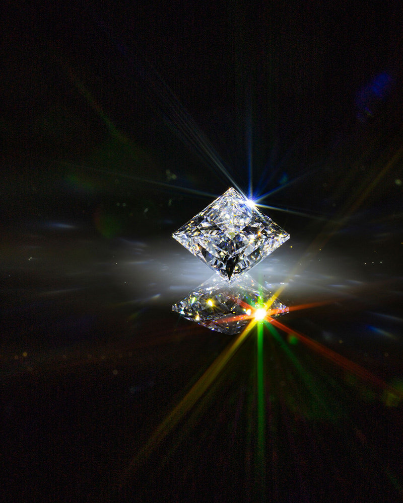 A synthetic diamond reflects rainbow shine on a black background.