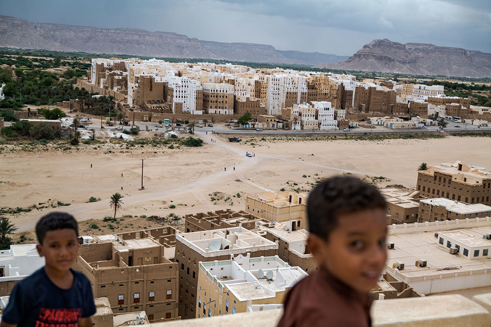 A picture of a city skyline where the houses are smooth, brown, and white. Two kids are in the foreground.