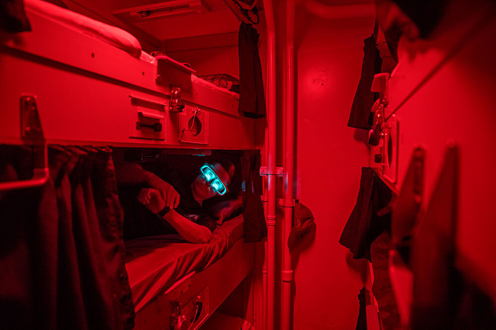 A man lies in a bunk wearing electric glasses