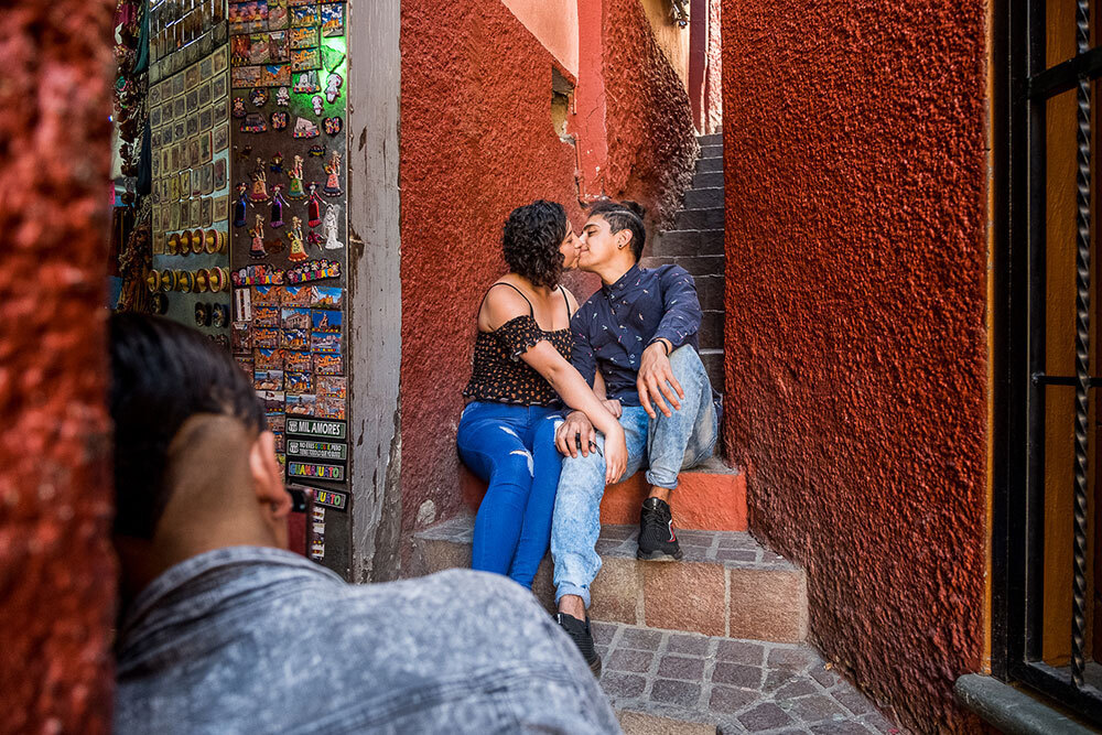 A couple kiss in a narrow, red passageway