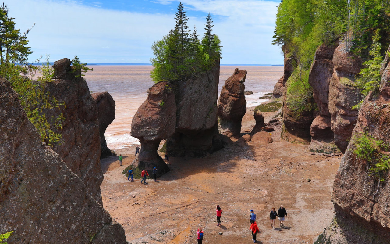 Tourists walk the beach at low tide at Hopewell Rocks in New Brunswick, Canada.