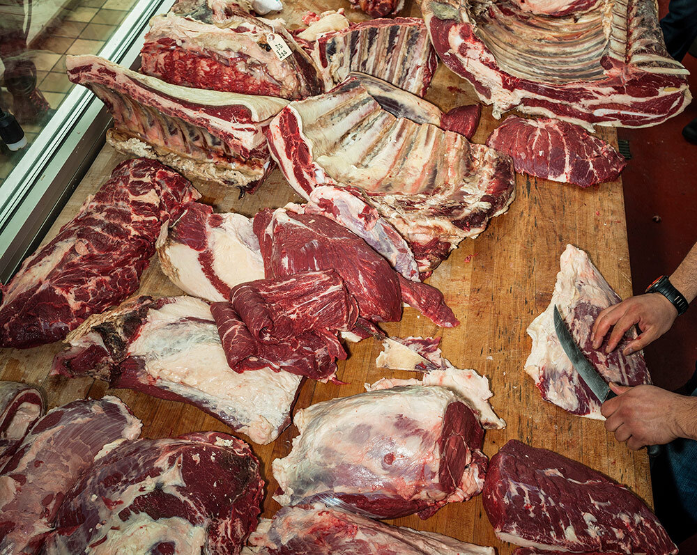 A butcher cutting a side of beef into various cuts.