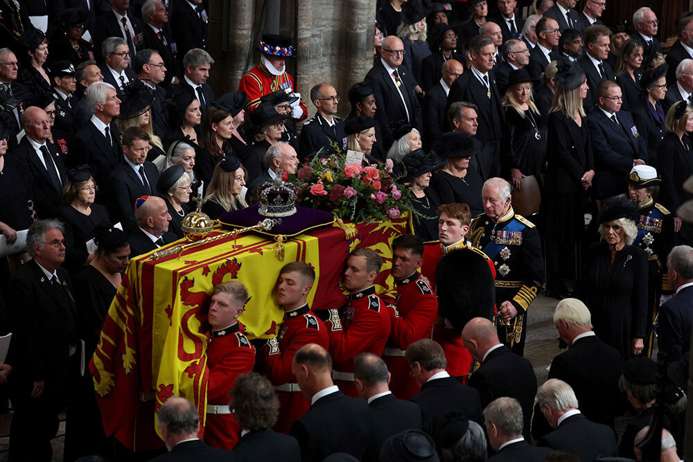 A coffin is carried through a sea of people in black