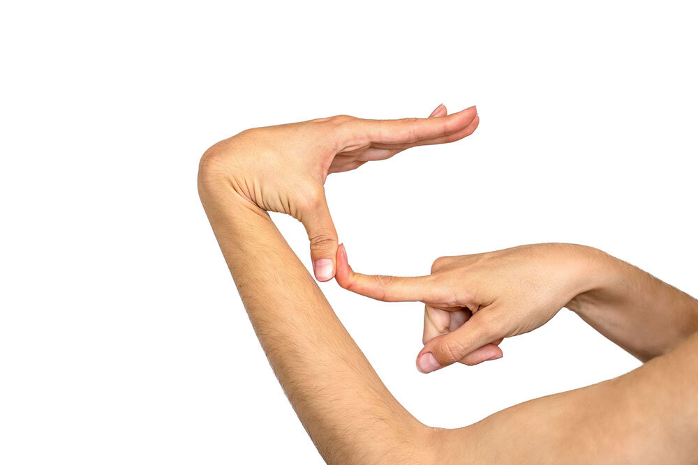 A hand demonstrating hyper-mobility of the thumb, which is able to bend back to almost touch its own arm