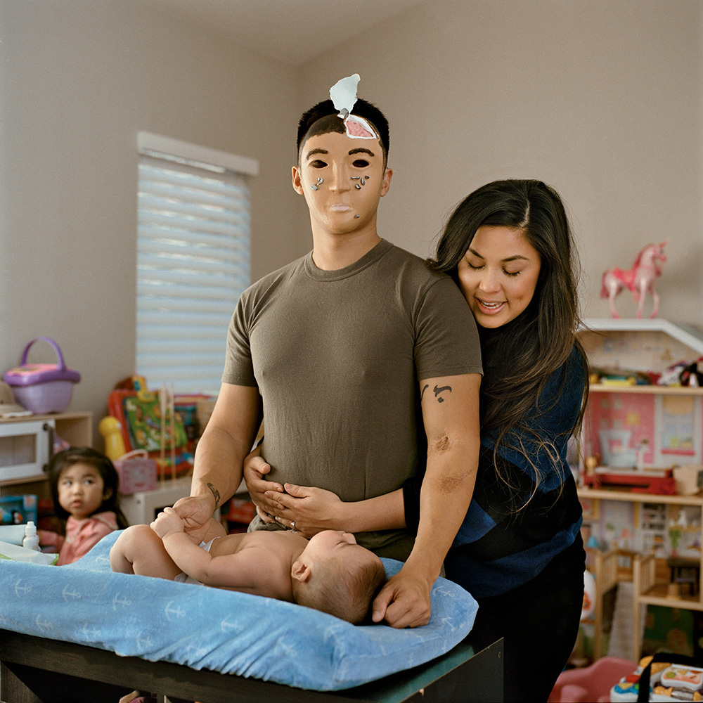 Retired Marine Gunnery Sgt. Aaron Tam, is photographed above with his wife, Angela, and the couple's two children. The Iraq War veteran is wearing a mask representing Tam’s own brain, one subjected to blast force explosions. He created the mask in an art therapy program designed to address the psychological health of veterans.