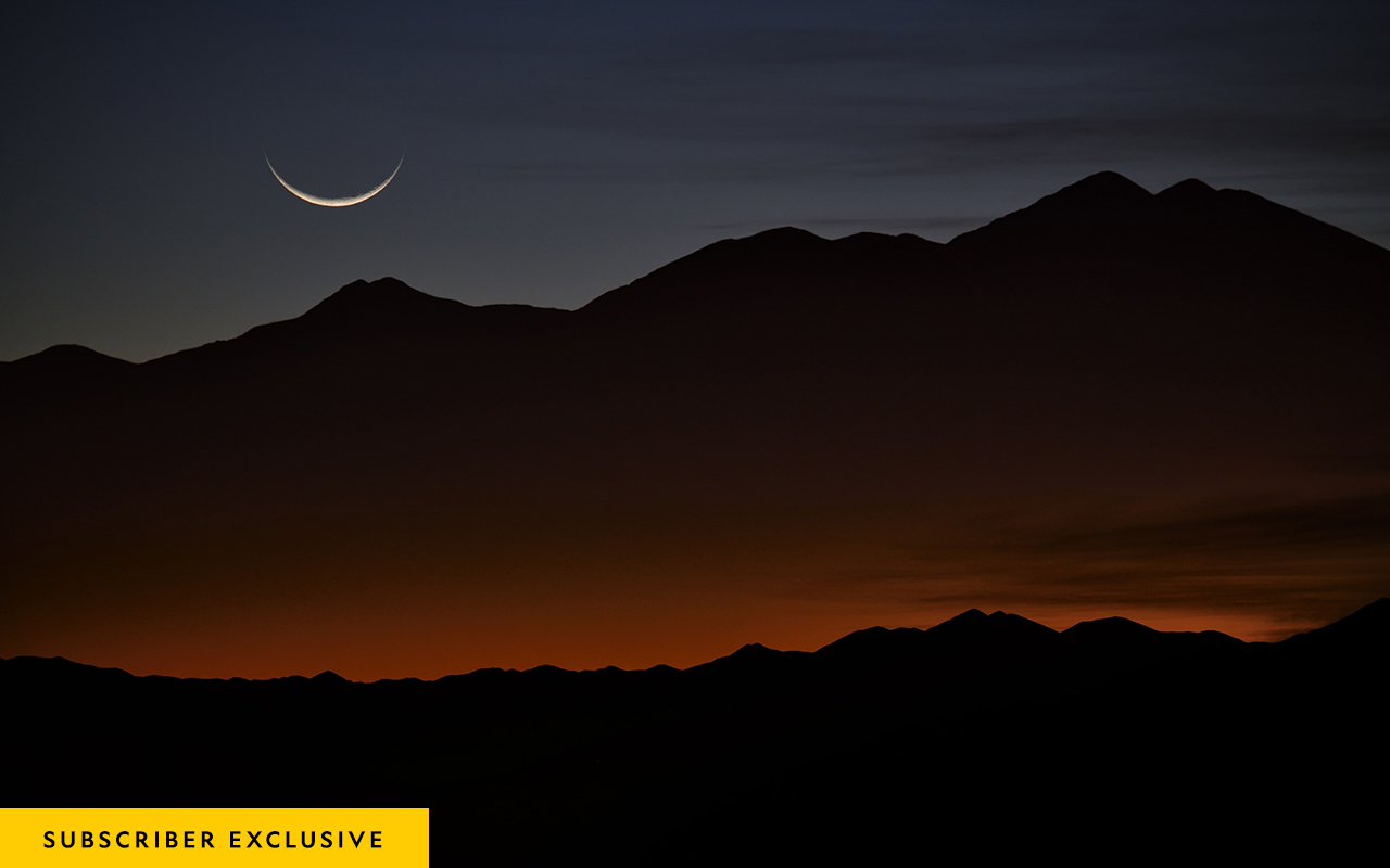 A crescent moon setting at sunrise over the mountains at Tolar Grande, Argentina.