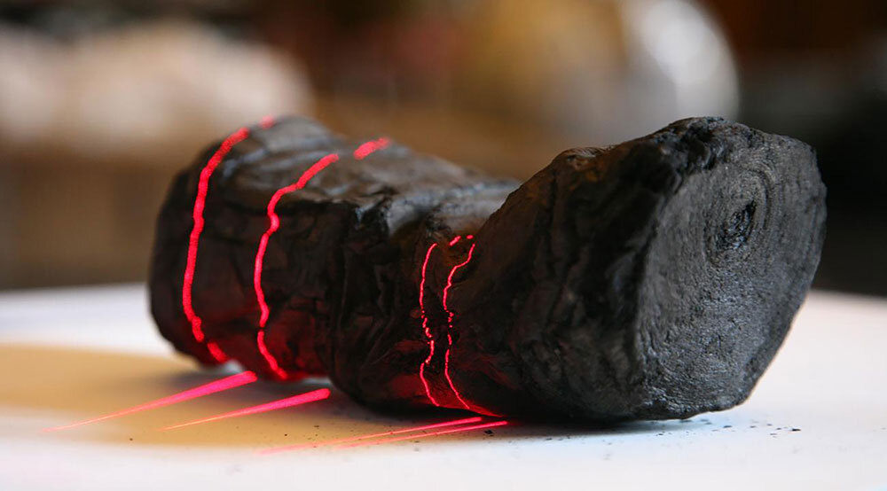 Herculaneum scroll with red laser lines being 3D scanned at Institut de France by Brent Seales and his team.