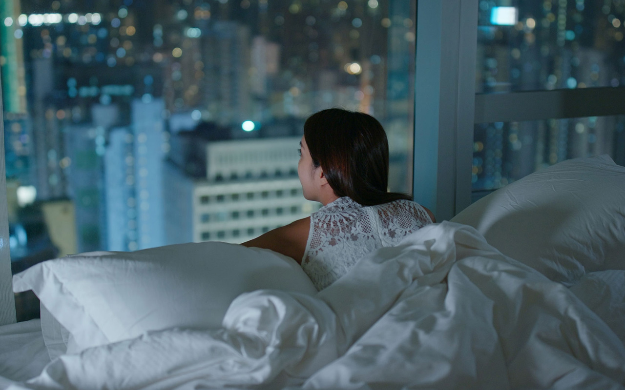 Woman lying in bed, gazing through window