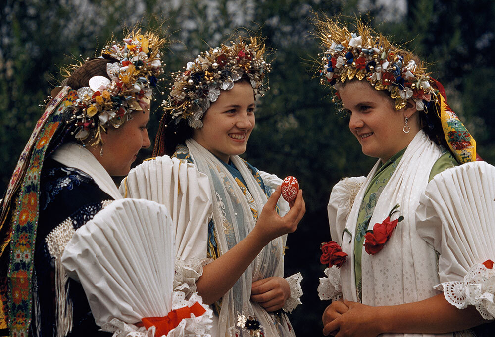 Austria women in traditional dress share eggs