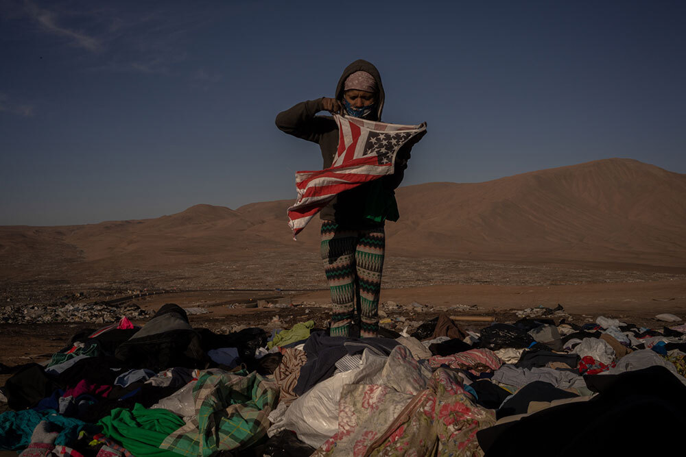 A woman holding up a garment in the desert