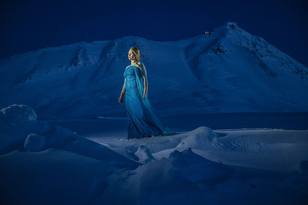 A picture of a woman wearing a long dress in a snow-covered landscape