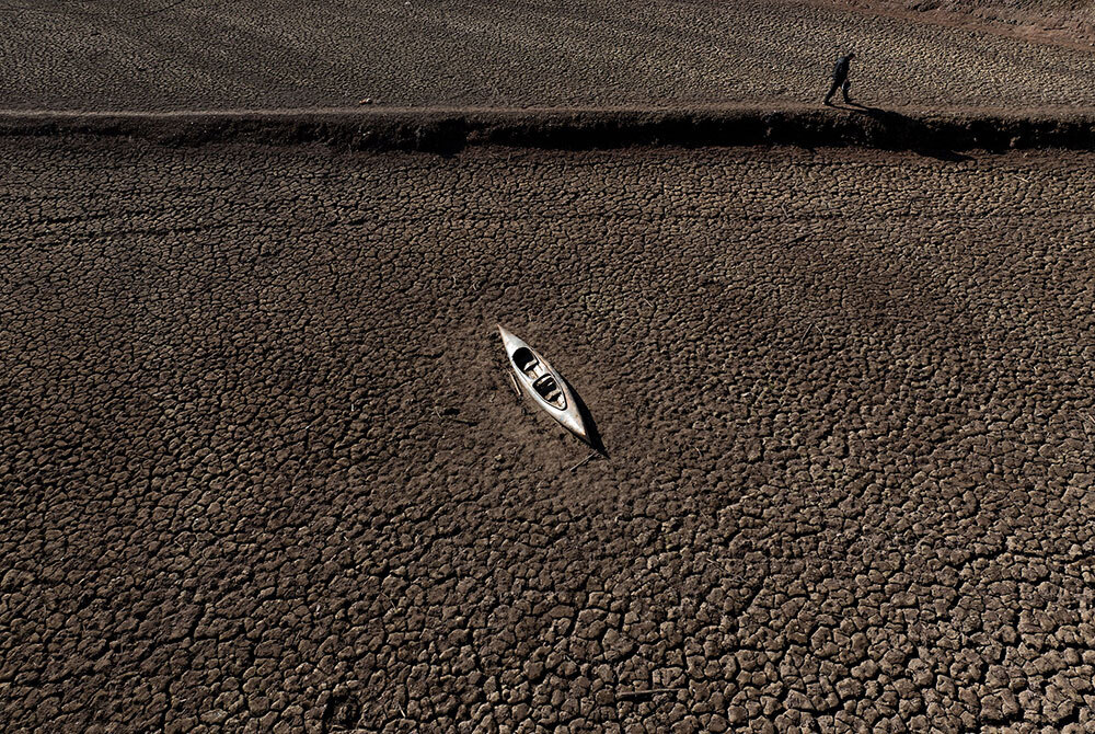 An arial image of a man walking past an abandoned canoe at San reservoir amid drought in Vilanova de San, Barcelona.