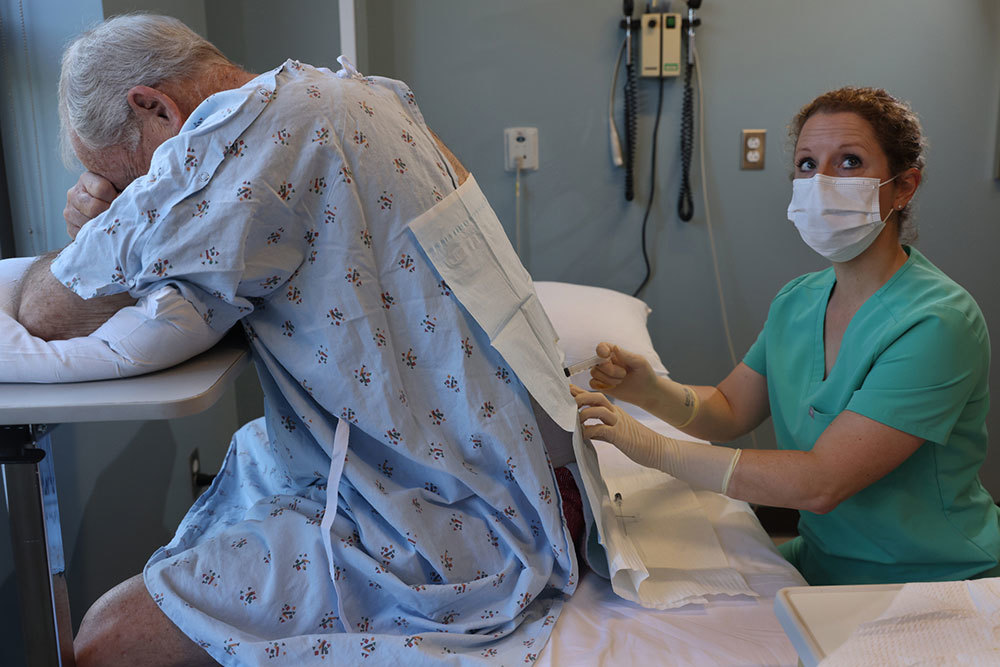 A picture of a physician holding a syringe against a man in a medical gown