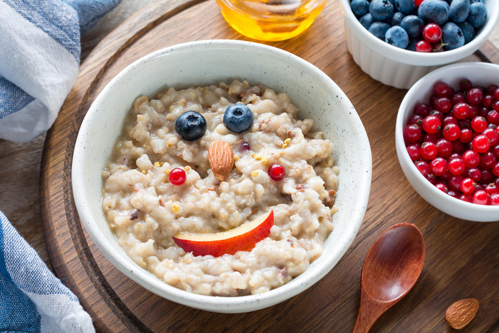 A bowl of oatmeal with a fruit smiley face