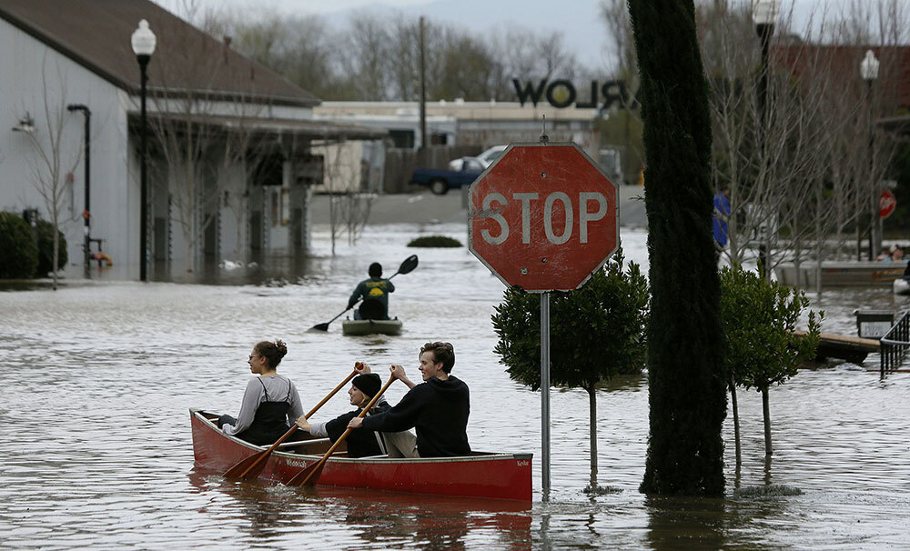 People paddle and row through the flooded Barlow Market District of Sebastopol, California, after an atmospheric river dumped inches of rain on the region in February, 2019.