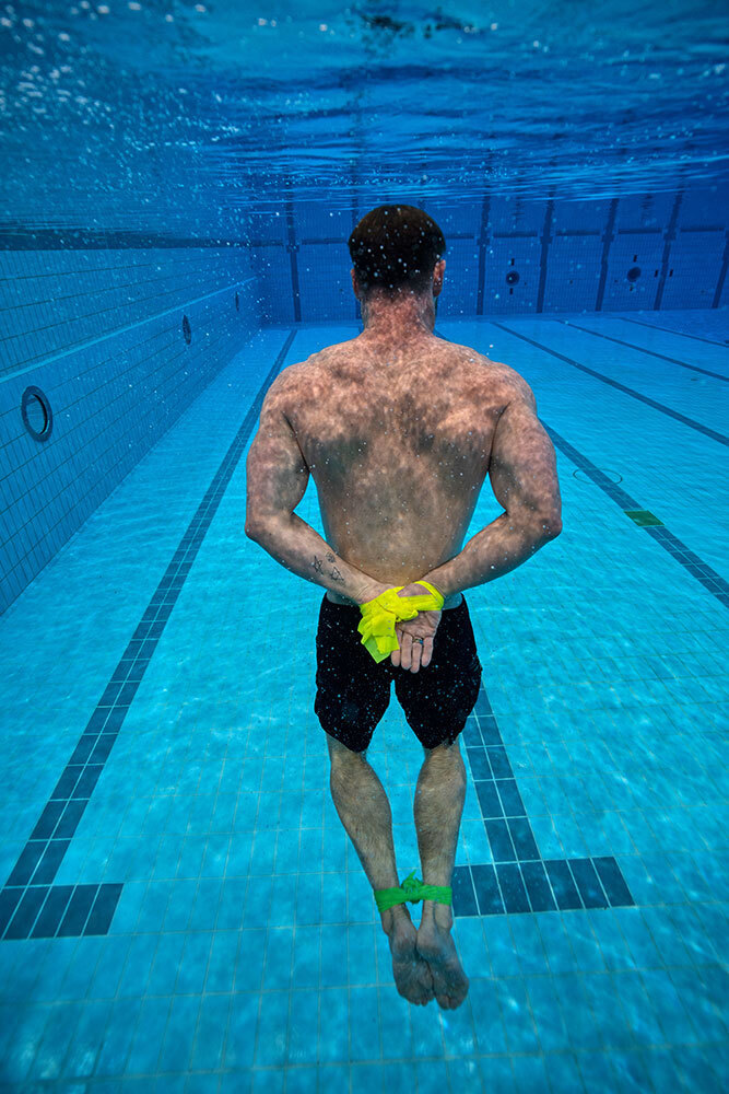 A picture of Chris Hemsworth underwater in a pool with his hands and feet bound