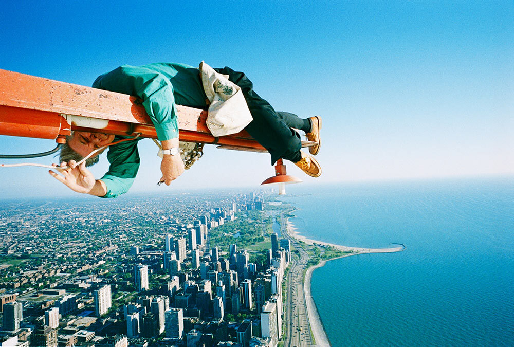 A man balances on Chicago’s John Hancock Center while fixing a cable.